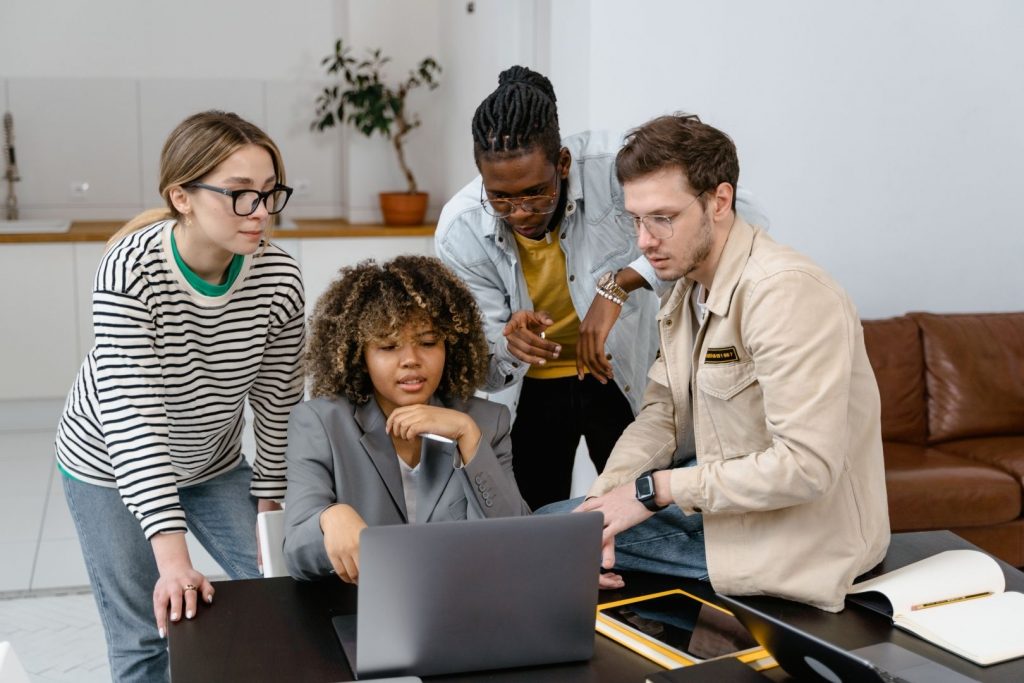 A diverse group of individuals looking at a laptop